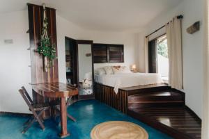 a bedroom with a bed and a desk and a table at Pousada Sossego in Pipa