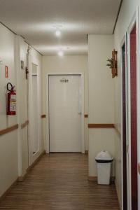 a hallway with a white door and a trash can at Hotel e Pousada Caroline in Foz do Iguaçu