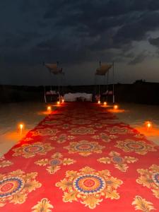 un lungo tappeto rosso con candele su una spiaggia di Best Desert Camp In Jaisalmer Red Velvet a Jaisalmer