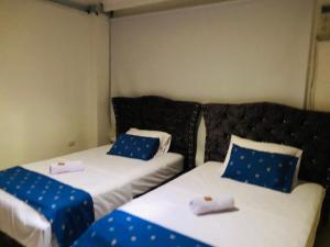 two beds in a room with blue and white pillows at Casa Blanca Guaviare Hostel in San José del Guaviare