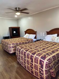 a hotel room with two beds and a ceiling fan at Hill Country Inn in Johnson City