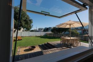a patio with a table and an umbrella at The Woodshed - Hot Stone Sauna & Ice Bath in Robe +27 photos