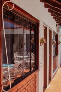 une fenêtre en verre d'un bâtiment avec une table et des chaises dans l'établissement Hotel e Pousada Caroline, à Foz do Iguaçu