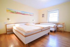 Habitación con 2 camas, suelo de madera y ventana. en Hof Köhne - Altes Bauernhaus - Wohnung Pony, en Schmallenberg