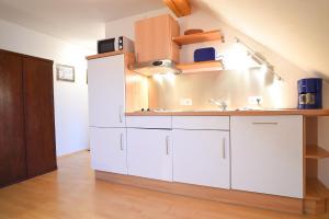 Una cocina con gabinetes blancos y un fregadero. en Hof Köhne - Altes Bauernhaus - Wohnung Dachstube links, en Schmallenberg