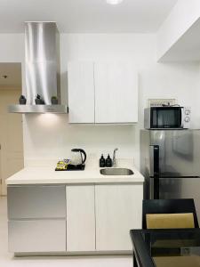 a white kitchen with a sink and a refrigerator at Beach Front Living in the Heart of the City, AZURE Residences in Manila
