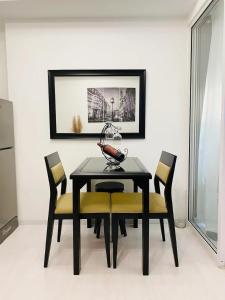 a dining room with a black table and yellow chairs at Beach Front Living in the Heart of the City, AZURE Residences in Manila