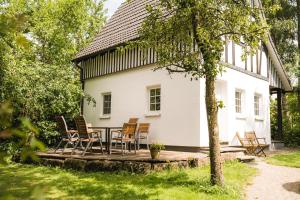 un tavolo e delle sedie su un ponte di fronte a una casa bianca di Hof Köhne - Malerhaus a Schmallenberg