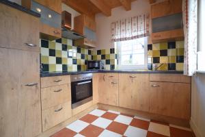 a kitchen with wooden cabinets and a checkered floor at Hof Köhne - Forsthaus 2er in Schmallenberg +42 photos