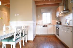 een keuken met witte kasten en een tafel en stoelen bij Hof Köhne - Haus an der Weide links in Schmallenberg