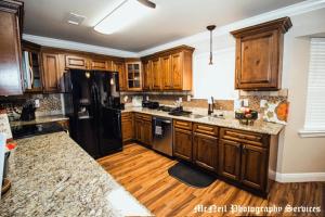 a kitchen with wooden cabinets and a black refrigerator at “Home Away From Home” ( HAFH) in Baton Rouge