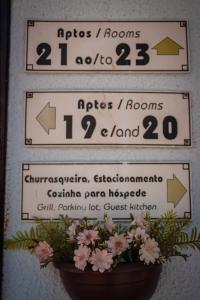 two signs on a wall with flowers in a pot at Hotel e Pousada Caroline in Foz do Iguaçu
