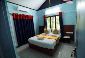 1 dormitorio con 1 cama con cortinas rojas y azules en NARMADA HOMESTAY Yamuna, en Malappuram