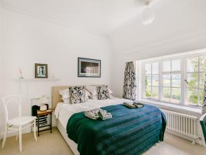 a white bedroom with a bed and a window at Castle Hill House in Sidbury