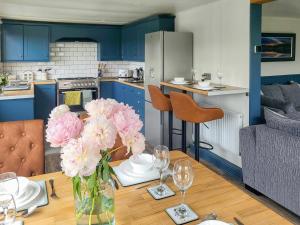 a kitchen with a table with a vase of flowers at Acre Hill Lodge in Harrop Fold