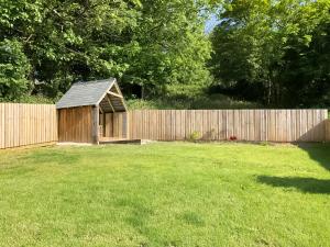 una piccola baracca di legno in un cortile accanto a una recinzione di April's Cottage a Kilkhampton