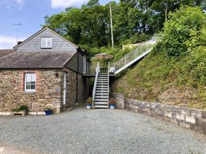 a house with a staircase leading up to a hill at Aprils Cottage in Kilkhampton