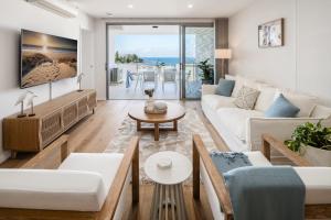a living room with white furniture and a view of the ocean at Azure Oceanside Apartment at Kings Beach in Caloundra