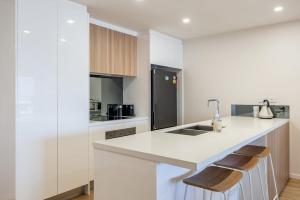 a kitchen with white countertops and a black refrigerator at Azure Oceanside Apartment at Kings Beach in Caloundra