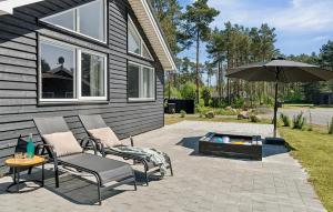 un patio con 2 sillas y una sombrilla en Pet Friendly Home In Nexø With Kitchen, en Neksø 19 fotos más