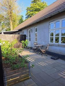 a house with a patio with a table and a fence at Hyggelig ferielejlighed i Harresø in Give