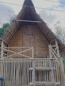 een houten hut met een bankje ervoor bij Bon Joy's Transient House in Mabini