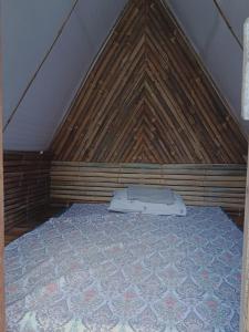 Bett in einem Zimmer mit Holzdach in der Unterkunft Bon Joy's Transient House in Mabini