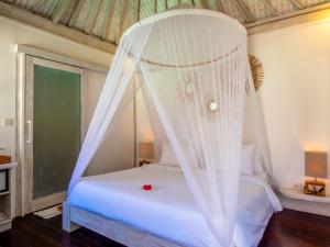 a bedroom with a white bed with a canopy at Ora Villas Gili Meno in Gili Meno