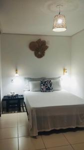 um quarto com uma grande cama branca e um relógio na parede em Suite Duplo Wind Jeri em Jericoacoara