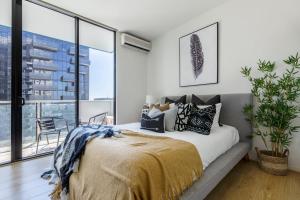 a bedroom with a bed with pillows and a large window at VAQUAY Scandi Boho In Docklands in Melbourne +40 photos