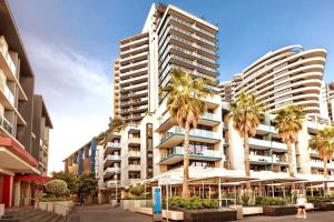 a tall building with palm trees in front of it at VAQUAY Scandi Boho In Docklands in Melbourne