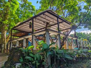 a small building with a roof in a garden at Kaliraya Surf Kamp by Eco Hotel Laguna in Cavinti