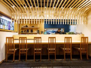 a bar with four chairs and a man in the kitchen at Tabist Hokkaido Daiichi Hotel Sapporo in Sapporo