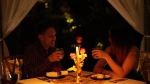 um homem e uma mulher sentados numa mesa com copos de vinho em Amora Ubud Boutique Villas em Ubud