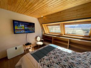 1 dormitorio con 1 cama, TV y ventana en Departamento en Edificio Atenas con excelentes Vistas en Las Lenas