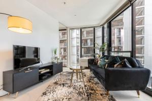 a living room with a black couch and a tv at VAQUAY Soho In Docklands in Melbourne