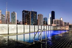 a swimming pool with a city skyline in the background at VAQUAY Soho In Docklands in Melbourne