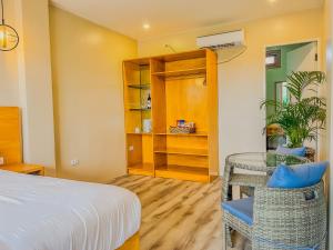 Sofia - Summer Coastal Suites في Bacnotan: غرفة نوم بسرير وطاولة وكرسي