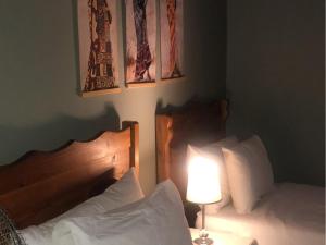 a bedroom with two beds and a lamp and paintings at Munati B&B in Musina