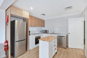 Una cocina con gabinetes blancos y un refrigerador de acero inoxidable. en The Entrance Hideaway, en The Entrance