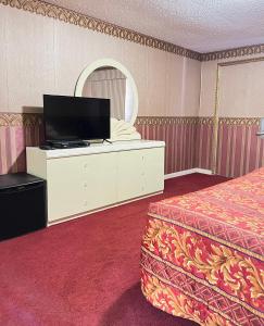 um quarto com uma cama e uma cómoda com uma televisão em Royal Inn - Neptune em Neptune City