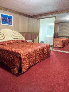 una camera d'albergo con un grande letto e uno specchio di Royal Inn - Neptune a Neptune City