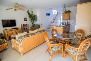 Una sala de estar con un sofá, una mesa y sillas. en GRACEBAY TOWNHOMES B3, 5 minutes walk to gracebay beach, en Long Bay Hills