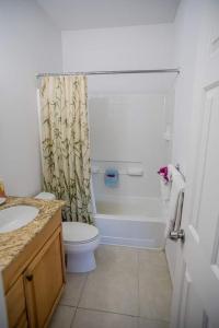 Un baño con inodoro y cortina de ducha. en GRACEBAY TOWNHOMES B3, 5 minutes walk to gracebay beach, en Long Bay Hills