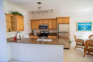 Una cocina con gabinetes de madera y un refrigerador de acero inoxidable. en GRACEBAY TOWNHOMES B3, 5 minutes walk to gracebay beach, en Long Bay Hills