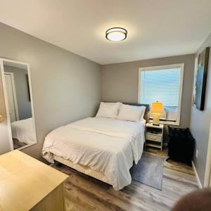 a bedroom with a bed and a lamp and a window at Ocean Block Oasis, 2-Bed Condo in Seaside Heights