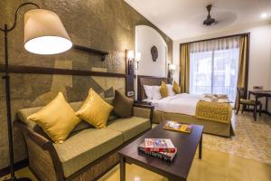 Rhythm Lonavala - An All Suite Resort في لونافالا: غرفة في الفندق مع أريكة وسرير