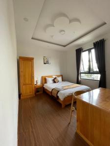 HANZ Hoa Dang Hotel في دالات: غرفة نوم فيها سرير وطاولة فيها