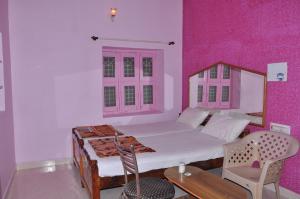 a bedroom with a bed and a pink wall at Thilak Home Stay in Hampi