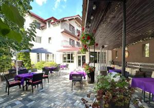 un patio avec des tables et des chaises violettes et un bâtiment dans l'établissement Vila Roca Hotel and SPA, à Valea Drăganului